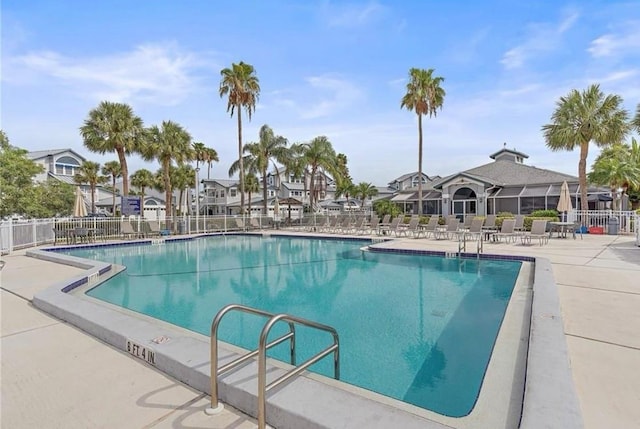 community pool featuring fence, a patio, and a residential view