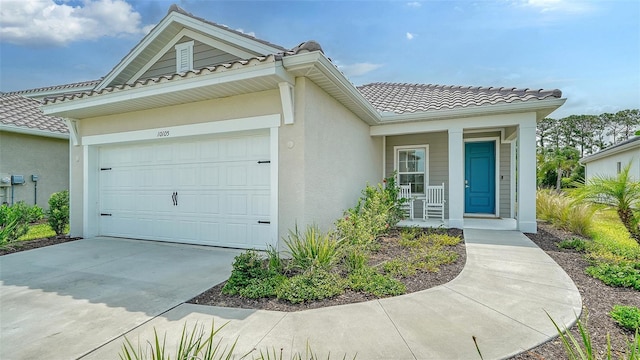 view of front of property with an attached garage, a tiled roof, stucco siding, and driveway