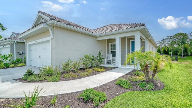 view of front facade featuring an attached garage, stucco siding, a tiled roof, a front lawn, and a porch