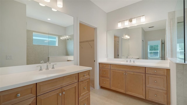 full bath with plenty of natural light, a walk in shower, and two vanities