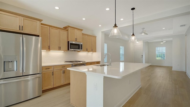 kitchen with appliances with stainless steel finishes, a sink, light brown cabinetry, a ceiling fan, and light wood-style floors