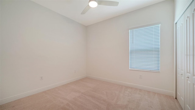 unfurnished room featuring light colored carpet, a ceiling fan, and baseboards