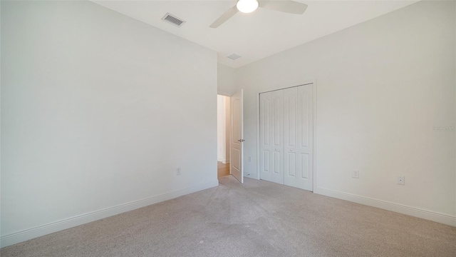 unfurnished bedroom featuring light colored carpet, a closet, baseboards, and a ceiling fan