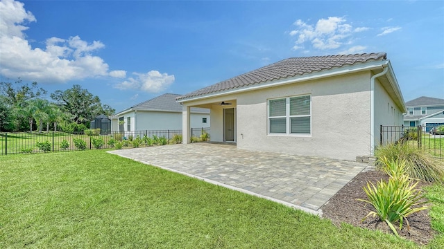 rear view of house featuring stucco siding, a patio, a tile roof, and a ceiling fan