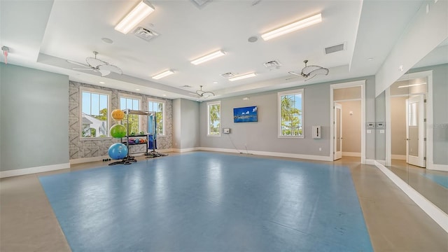 exercise area with a tray ceiling and healthy amount of natural light