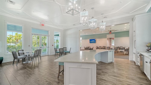 kitchen featuring a kitchen island, a breakfast bar, light wood-type flooring, white cabinets, and decorative light fixtures