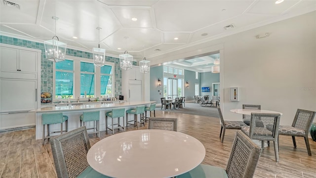 dining room featuring coffered ceiling, light wood-type flooring, recessed lighting, and ornamental molding
