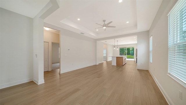 10105 Canaveral Cir, Sarasota, FL 34241 - unfurnished living room featuring ceiling fan, a raised ceiling, light wood-type flooring, recessed lighting, and baseboards