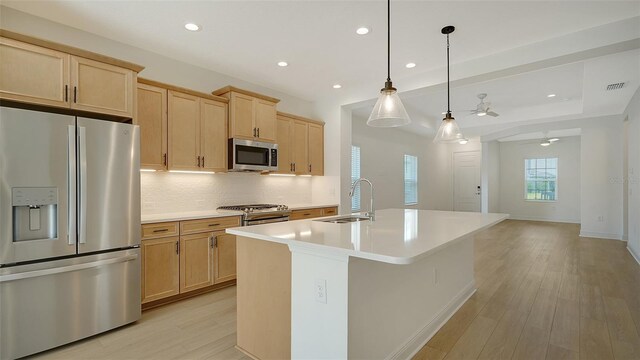 10105 Canaveral Cir, Sarasota, FL 34241 - kitchen with stainless steel appliances, a sink, light brown cabinetry, a ceiling fan, and backsplash