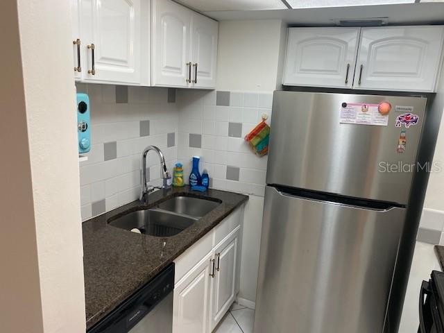 6157 E Midnight Pass Rd Unit B51, Sarasota, FL 34242 - kitchen with stainless steel appliances, a sink, dark stone countertops, white cabinetry, and backsplash
