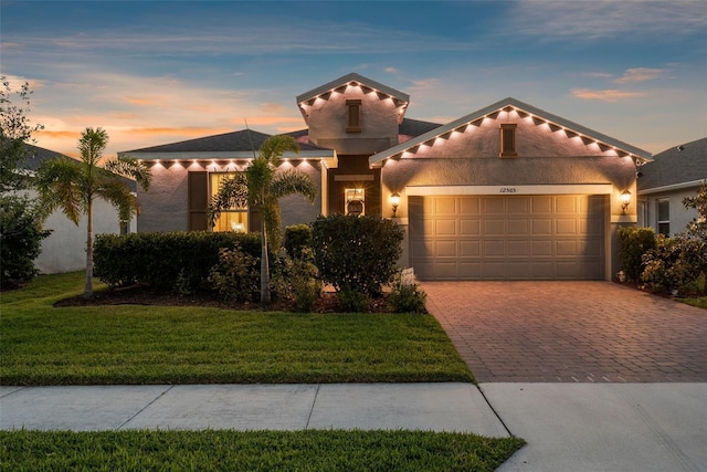 view of front facade featuring a garage, a front lawn, stucco siding, and decorative driveway