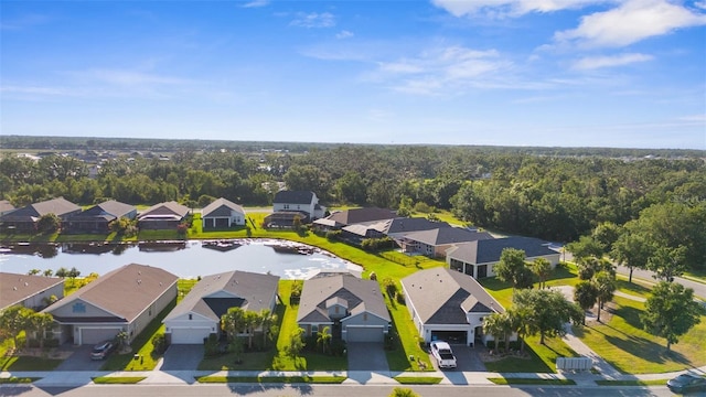 bird's eye view featuring a wooded view, a residential view, and a water view