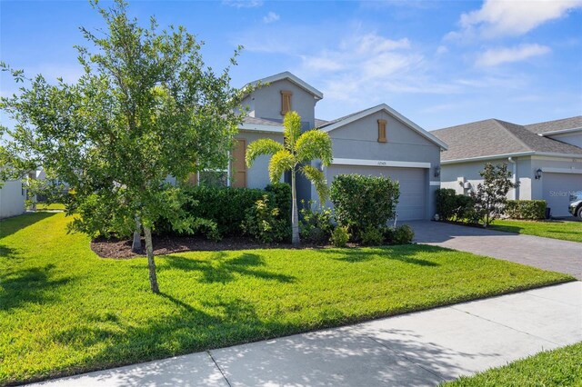 view of front of property with an attached garage, a front lawn, decorative driveway, and stucco siding
