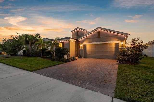 view of front of house with a tiled roof, a yard, stucco siding, decorative driveway, and a garage