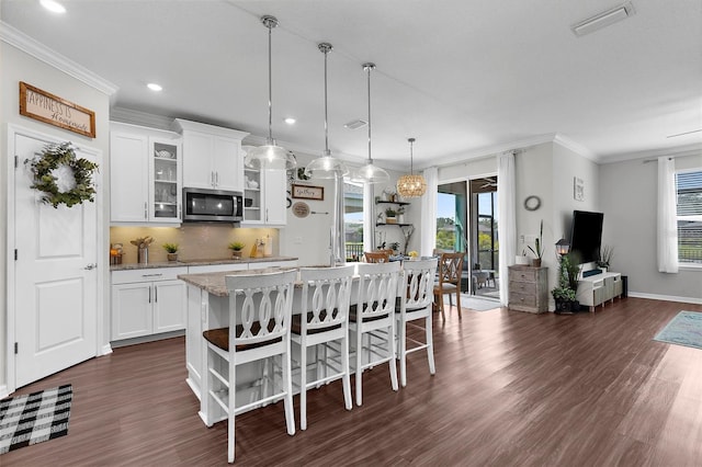 kitchen with a wealth of natural light, stainless steel microwave, and dark wood finished floors