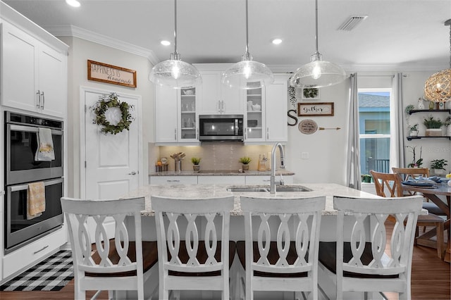 kitchen featuring white cabinets, a sink, visible vents, appliances with stainless steel finishes, and ornamental molding