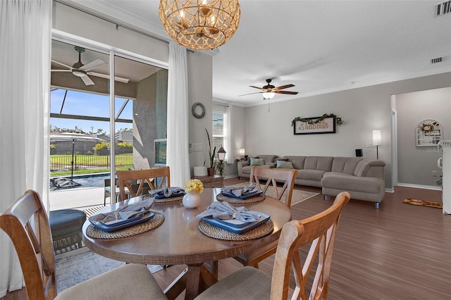 dining space featuring ceiling fan with notable chandelier, wood finished floors, baseboards, and visible vents