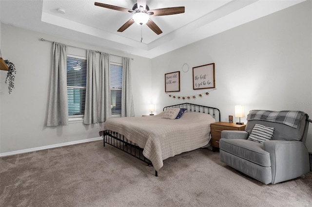carpeted bedroom with baseboards, a ceiling fan, and a tray ceiling