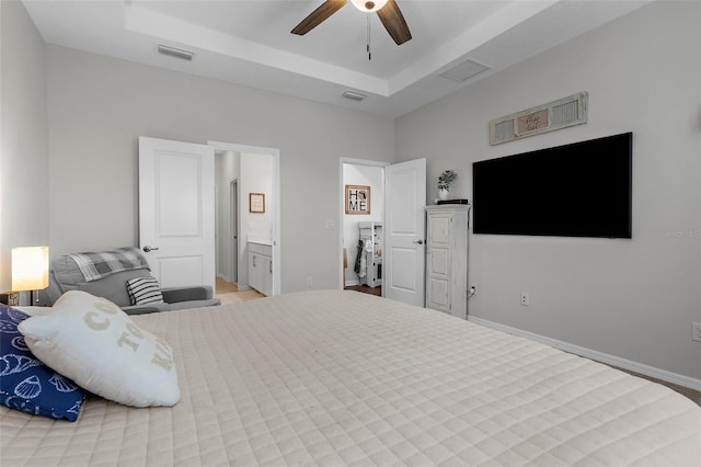 bedroom featuring ensuite bath, a raised ceiling, and visible vents