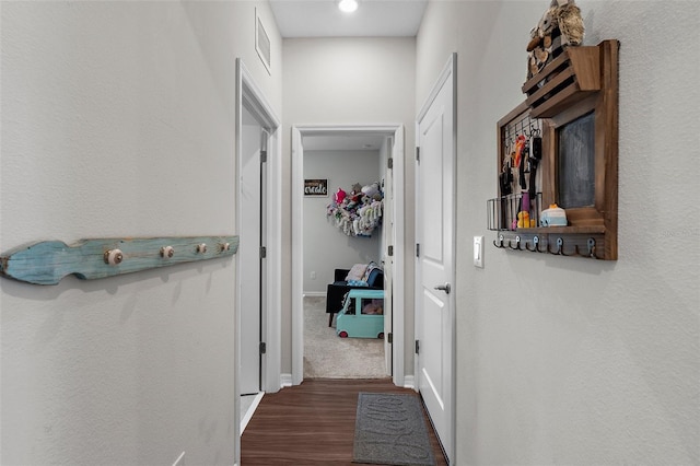 hall with baseboards, wood finished floors, and visible vents