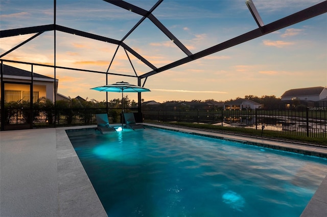 pool at dusk featuring glass enclosure, fence, and a fenced in pool