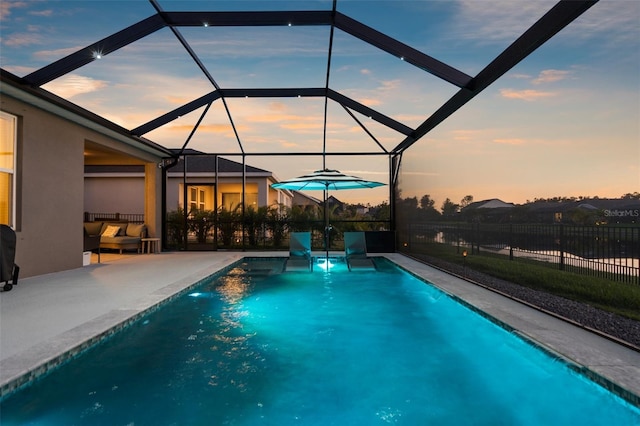 pool at dusk with fence, a patio area, a fenced in pool, and glass enclosure