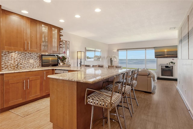 4800 Gulf Of Mexico Dr Unit 205, Longboat Key, FL 34228 - kitchen featuring brown cabinetry, a breakfast bar area, light wood-type flooring, recessed lighting, and open floor plan
