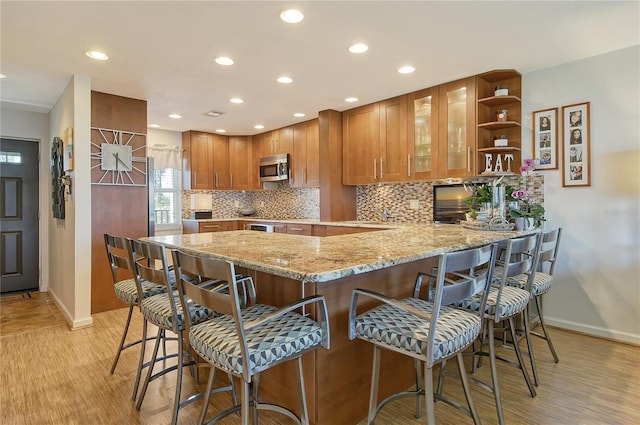 4800 Gulf Of Mexico Dr Unit 205, Longboat Key, FL 34228 - kitchen featuring stainless steel microwave, a peninsula, decorative backsplash, light stone counters, and recessed lighting