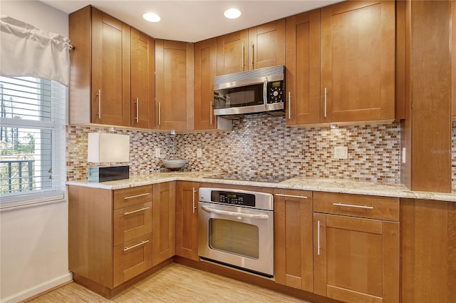 4800 Gulf Of Mexico Dr Unit 205, Longboat Key, FL 34228 - kitchen featuring stainless steel appliances, tasteful backsplash, brown cabinets, light stone countertops, and recessed lighting