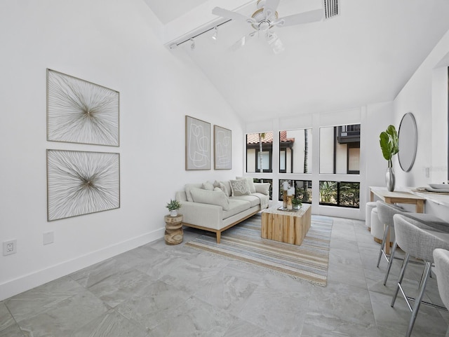 living area with high vaulted ceiling, track lighting, a ceiling fan, light marble finish flooring, and baseboards