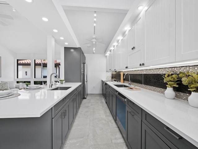 kitchen featuring a sink, ceiling fan, stainless steel dishwasher, tasteful backsplash, and light countertops
