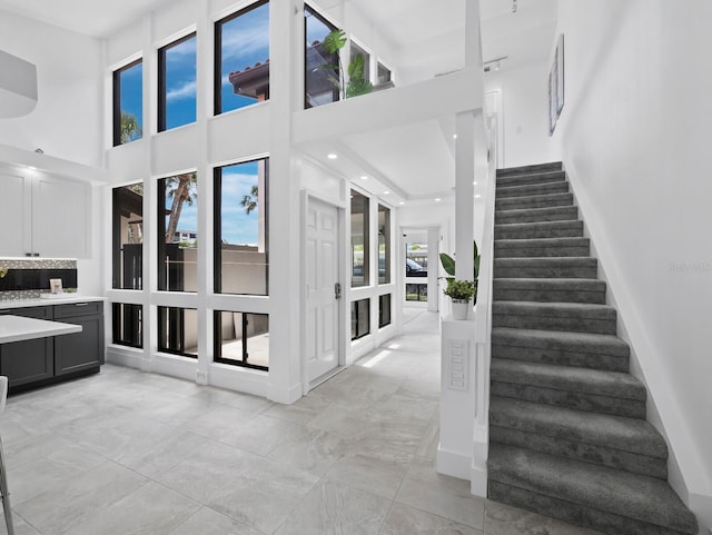 stairs with a towering ceiling, baseboards, and recessed lighting