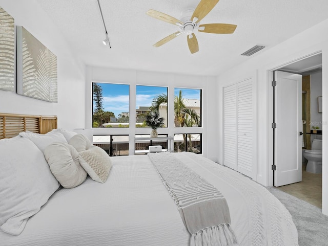 bedroom with a textured ceiling, ceiling fan, and rail lighting