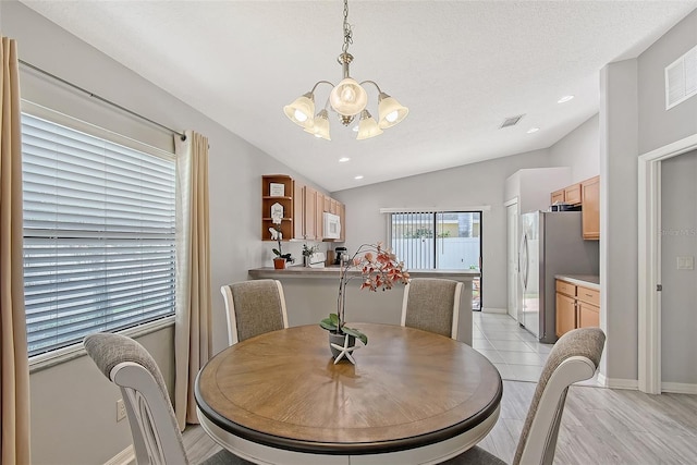 dining room with vaulted ceiling, a chandelier, baseboards, and visible vents