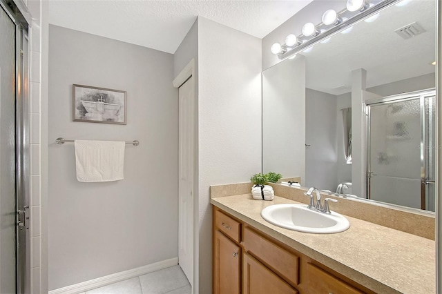 full bath with vanity, visible vents, a stall shower, tile patterned flooring, and baseboards