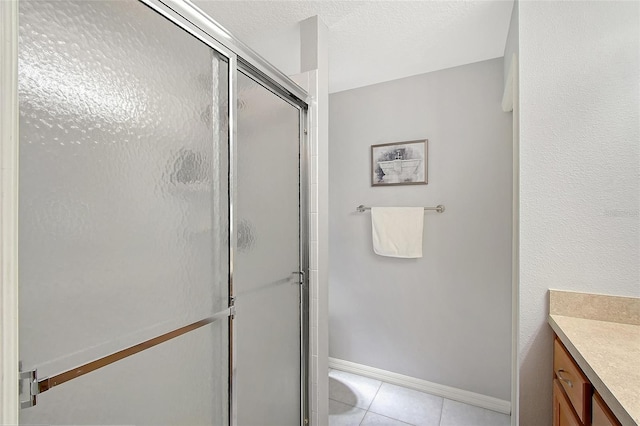 full bathroom with a stall shower, vanity, baseboards, and tile patterned floors