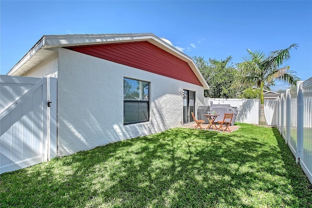 back of property featuring a yard, stucco siding, and a fenced backyard