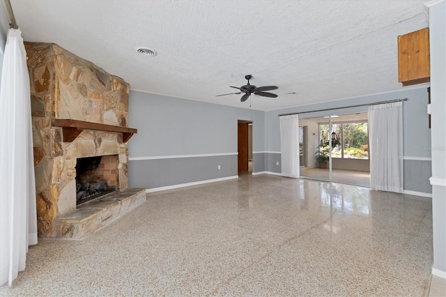 4311 52nd St E, Bradenton, FL 34208 - unfurnished living room featuring ceiling fan, a stone fireplace, a textured ceiling, visible vents, and speckled floor