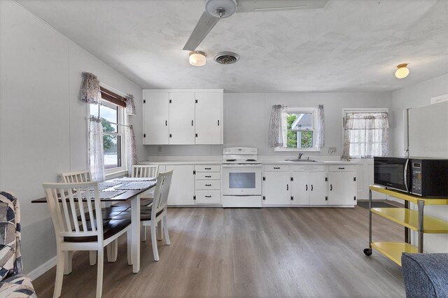 4311 52nd St E, Bradenton, FL 34208 - kitchen with visible vents, black microwave, white electric range oven, light wood-type flooring, and light countertops