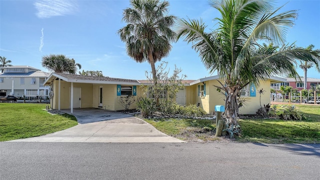 ranch-style house with concrete driveway, a front yard, and a carport
