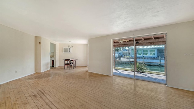 unfurnished room with baseboards, an inviting chandelier, and light wood-style flooring