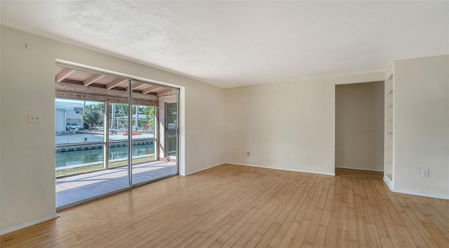 spare room with baseboards and hardwood / wood-style floors