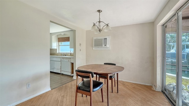 dining room featuring baseboards, light wood-style flooring, a wall mounted AC, and a chandelier