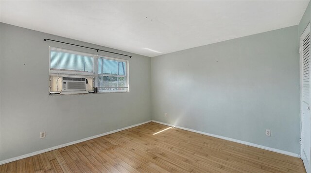spare room with light wood-style floors, baseboards, and cooling unit