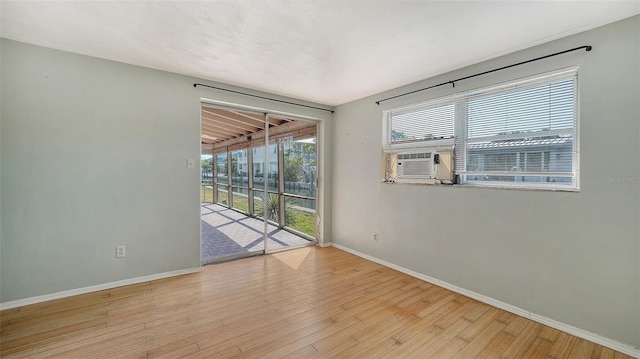 spare room featuring baseboards, wood finished floors, and cooling unit
