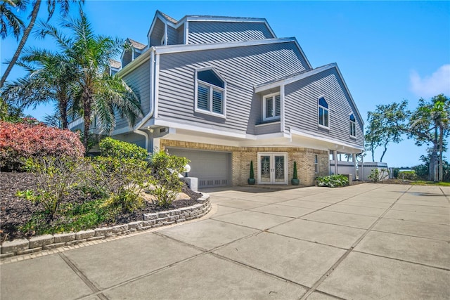 view of front of property with brick siding, driveway, french doors, and a garage