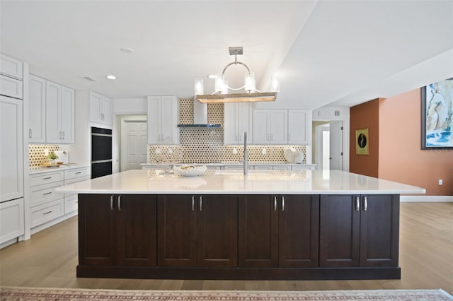 kitchen with a sink, light countertops, tasteful backsplash, and white cabinets