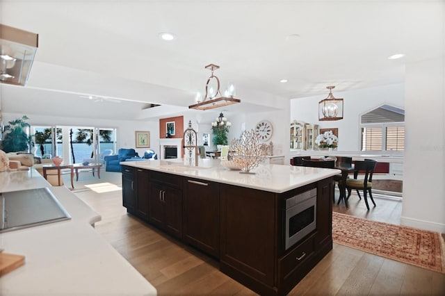 kitchen featuring light countertops, stainless steel microwave, light wood finished floors, open floor plan, and an inviting chandelier