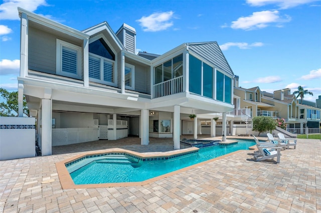 back of house with a pool with connected hot tub and a patio area