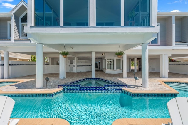 outdoor pool featuring a patio, an in ground hot tub, and fence